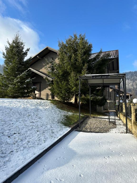 a house with a snow covered yard with a bench at Bozhena in Mykulychyn