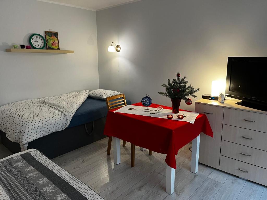 ein Schlafzimmer mit einem Tisch, einem Bett und einem TV in der Unterkunft U Wisi in Wałbrzych