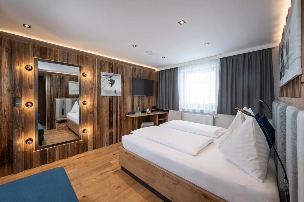 a hotel room with a large bed and a mirror at Austria Alpinhotel in Obertauern