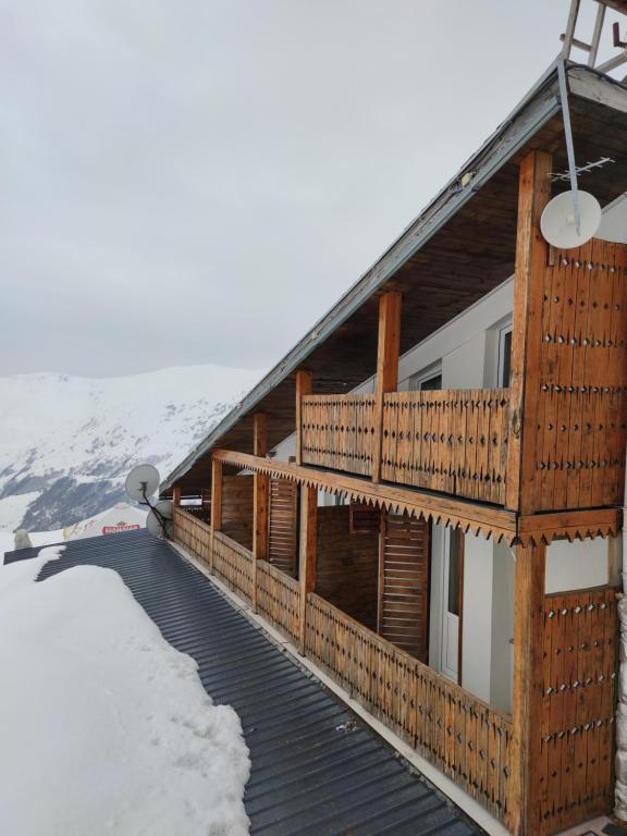 a building with a wooden deck in the snow at Hotel Zemo Aragvi in Gudauri