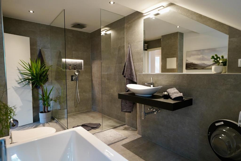 La salle de bains est pourvue d'un lavabo, d'une baignoire et d'un miroir. dans l'établissement EDLER WOHNRAUM Noble Stadtoase im Zentrum mit Parkplatz, Boxspringbett & Einbaukaffeevollautomat, à Zwickau