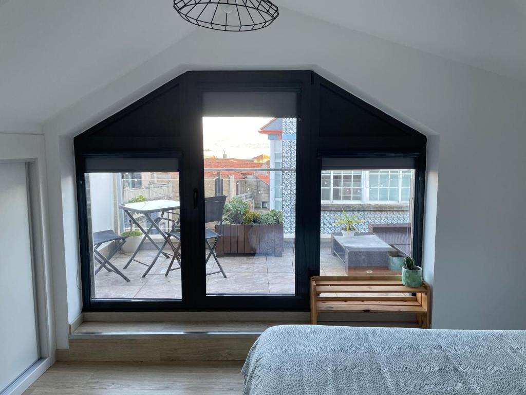 Schlafzimmer mit einem großen Fenster mit Blick auf einen Innenhof in der Unterkunft Duplex Casa da barbeira in Cangas