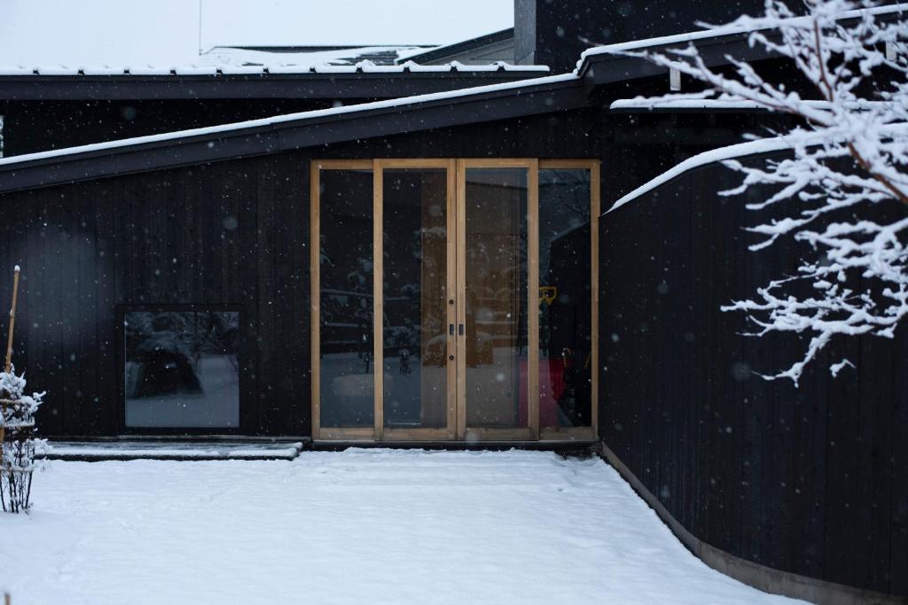 a black building with glass doors in the snow at こもる五所川原 in Goshogawara