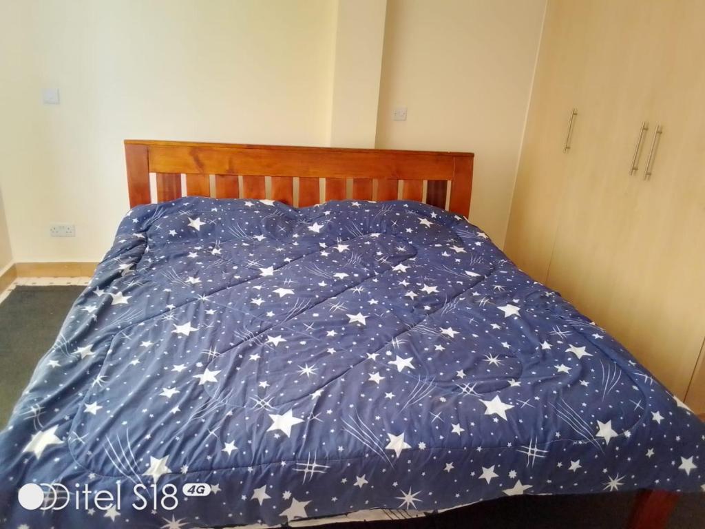 a bed with a blue comforter with stars on it at Nhc Langata Court Mall in Nairobi