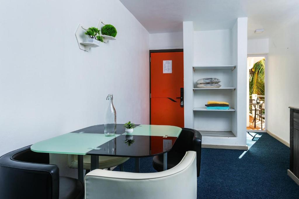 a dining room with a table and chairs and a red door at C-view Apartments in Flic-en-Flac