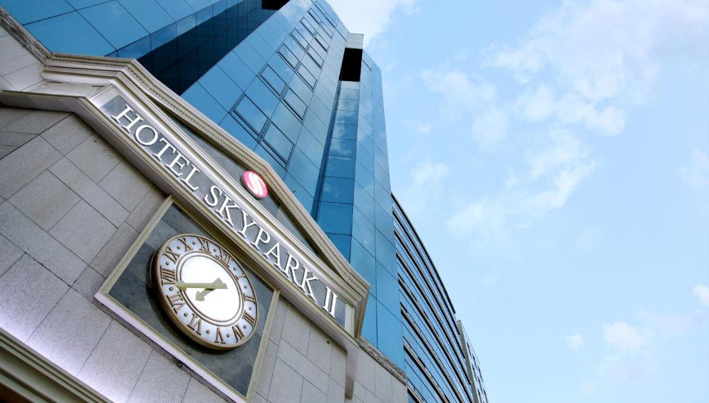 eine Uhr auf der Seite eines Gebäudes mit einem Wolkenkratzer in der Unterkunft Hotel Skypark Myeongdong 2 in Seoul