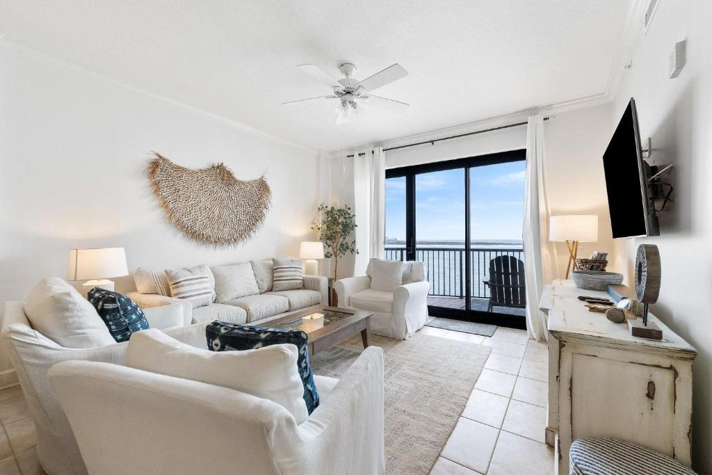 sala de estar con muebles blancos y ventana grande en Grand Pointe 401 en Orange Beach