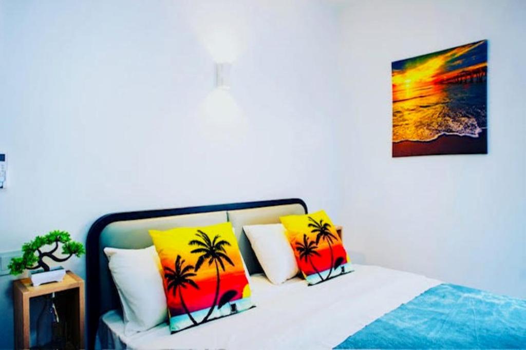 a bed with four pillows with palm trees on it at C-view Apartments in Flic-en-Flac