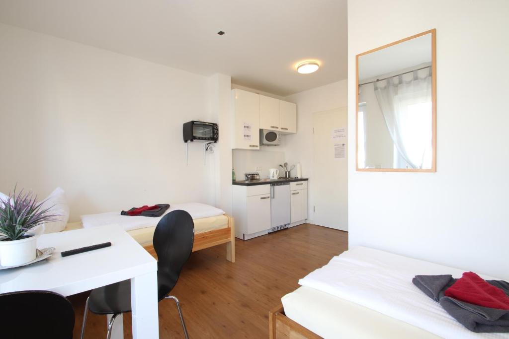 アシャッフェンブルクにあるApartments/Wohnungen direkt in Aschaffenburgのベッド2台、テーブル、椅子が備わる小さな客室です。