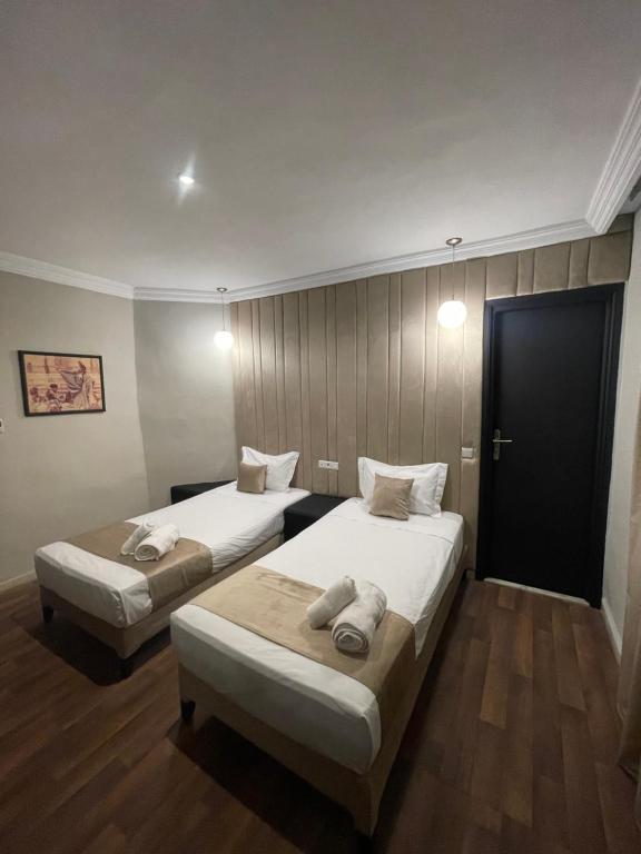 two beds in a hotel room with a door at Cadé Hotel in Casablanca