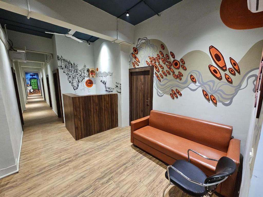 een lobby met een bank en een muur met een muurschildering bij MY ROOMZ BANARAS in Varanasi