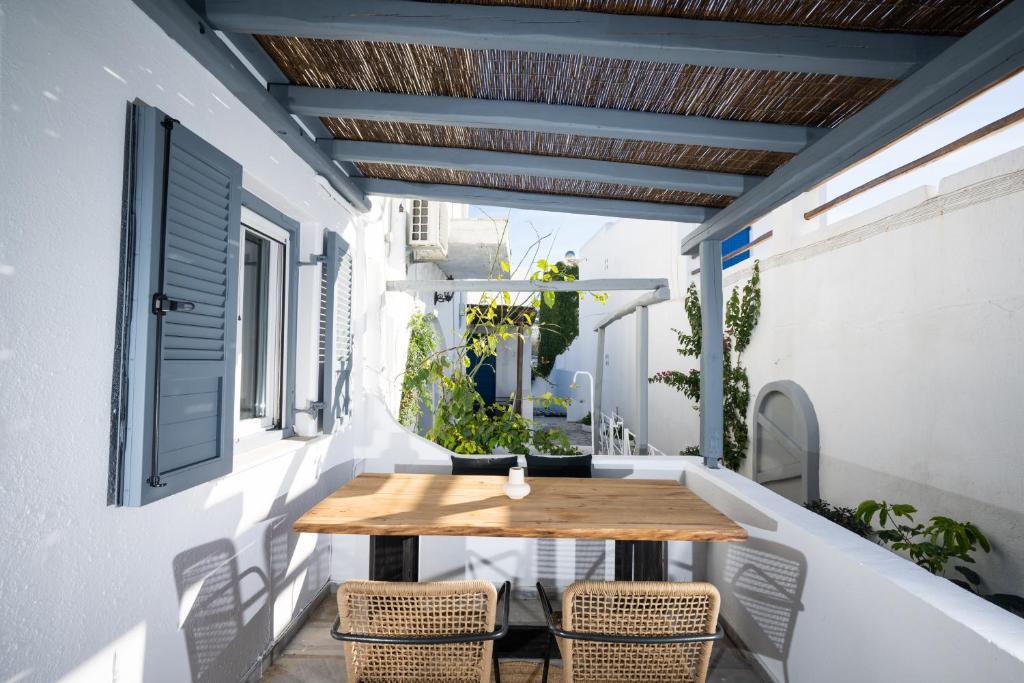 an outdoor patio with a wooden table and chairs at Loom Suite Ornos in Mikonos