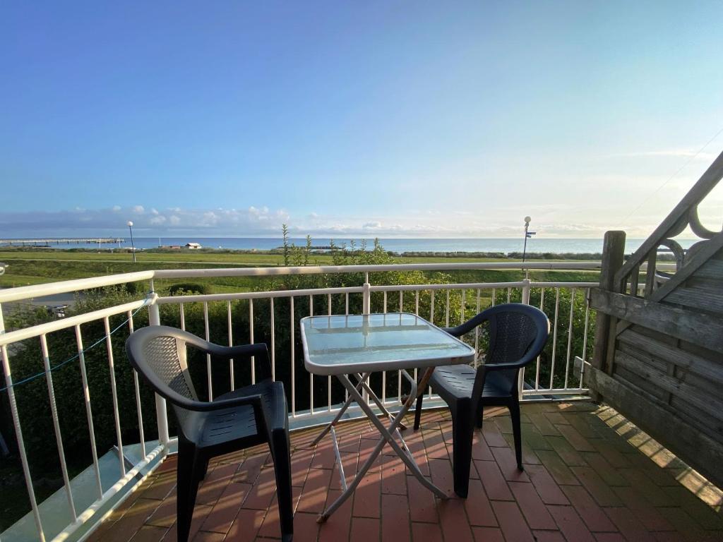 einen Tisch und zwei Stühle auf einem Balkon mit Meerblick in der Unterkunft Ostseesicht in Schönberger Strand