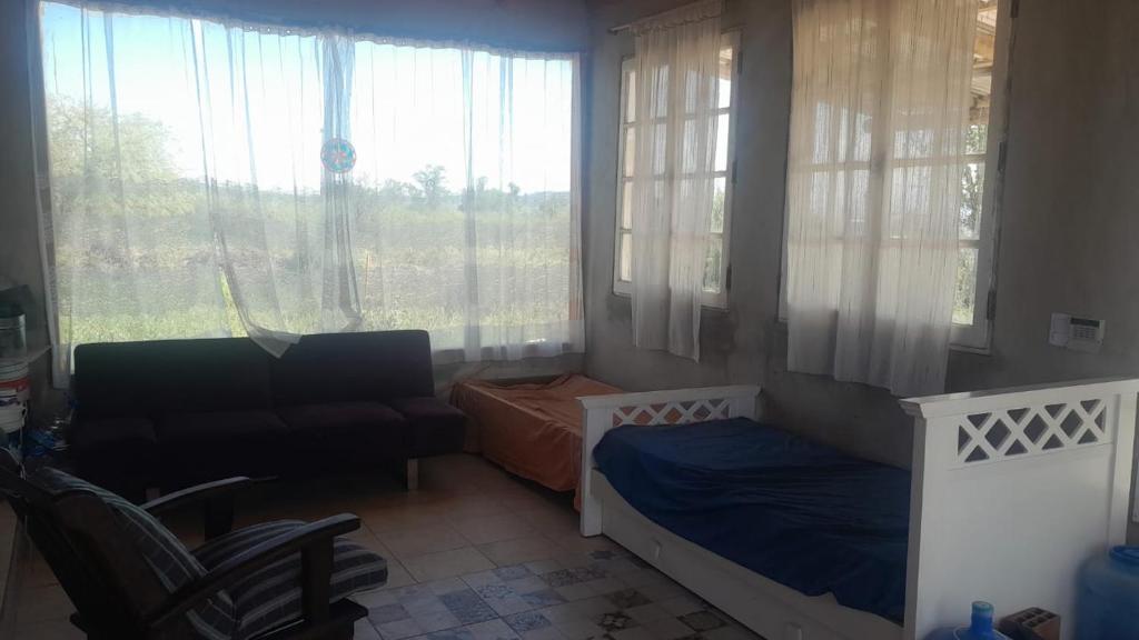 1 dormitorio con 2 camas, silla y ventanas en La Apacheta en San Roque