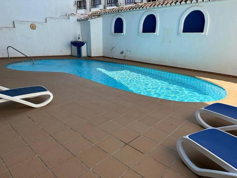 una piscina con 2 tumbonas frente a un edificio en Preciosa casa adosada en Mijas en Mijas