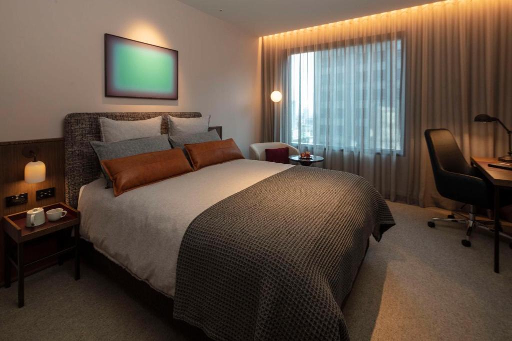 a bedroom with a bed and a desk and a chair at Next Hotel Melbourne, Curio Collection by Hilton in Melbourne