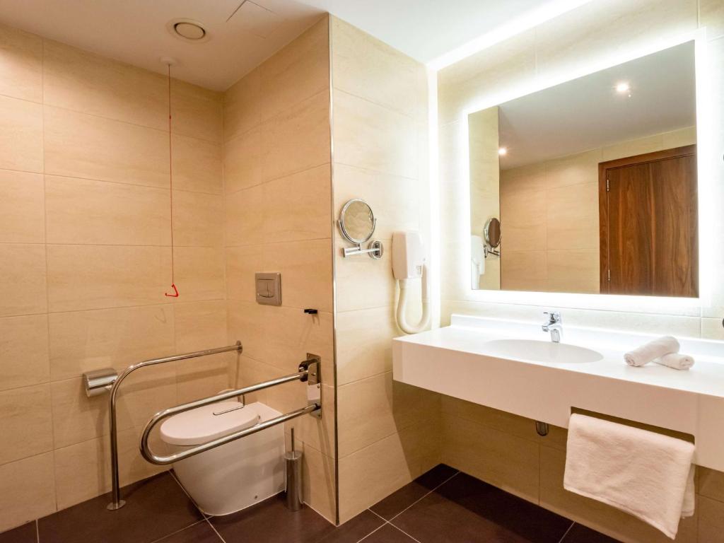 a bathroom with a sink and a toilet and a mirror at DoubleTree by Hilton Malta in St Paul's Bay