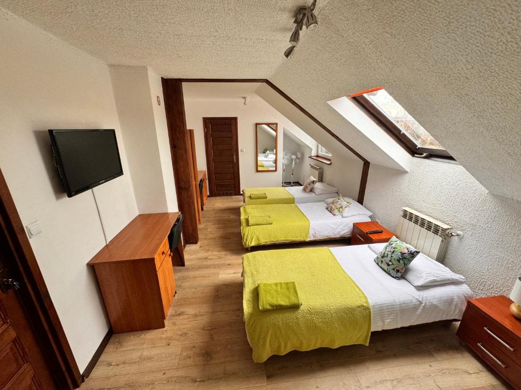 a hotel room with two beds and a flat screen tv at Villa Beata in Nowy Sącz