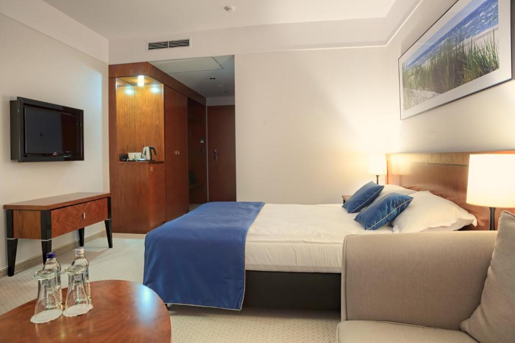 a hotel room with a bed and a couch at Grand Lubicz Uzdrowisko Ustka in Ustka