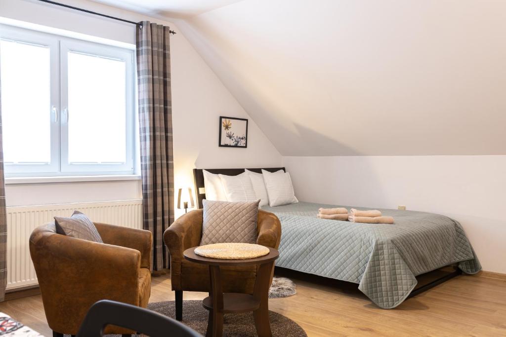 a bedroom with a bed and two chairs and a window at Molonówka Guest House in Szczyrk