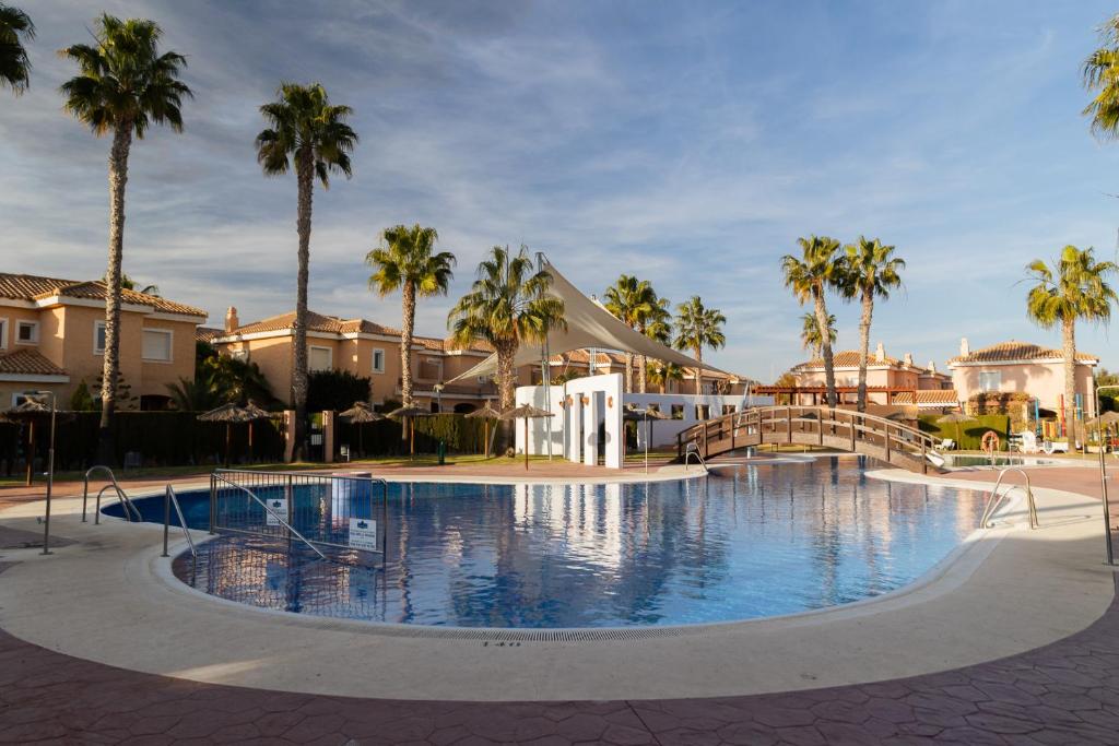 a large swimming pool with palm trees and houses at Chill-out # Piscina todo el año # Playa a 650m in Vera