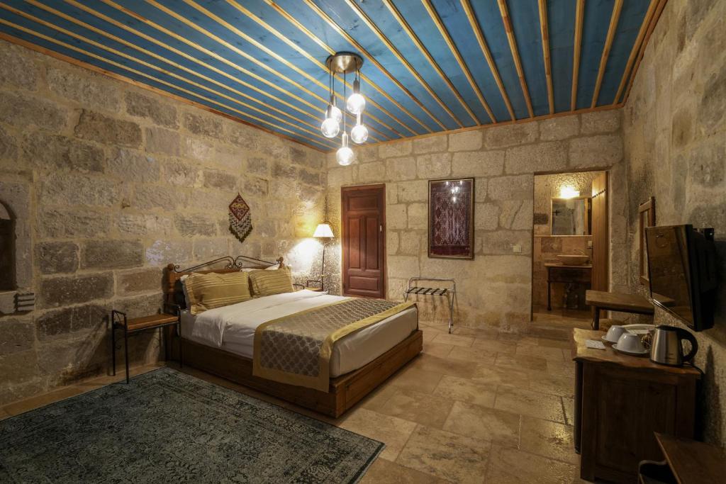 1 dormitorio con 1 cama en una habitación con paredes de piedra en Tekkaya Cave Hotel, en Göreme