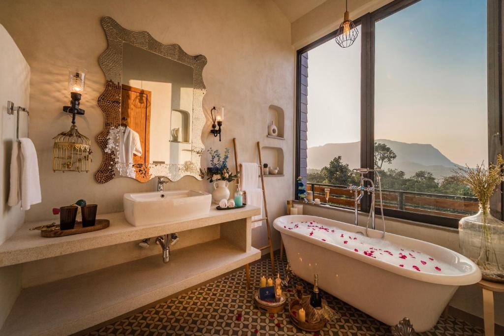 een badkamer met een bad, een wastafel en een spiegel bij SaffronStays SATORI in Mulshi