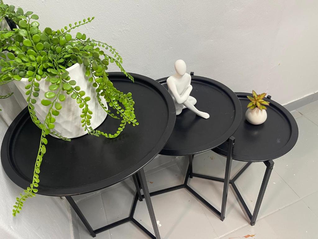 two black tables with a plant and a white vase at Pelican Apartment in Durban