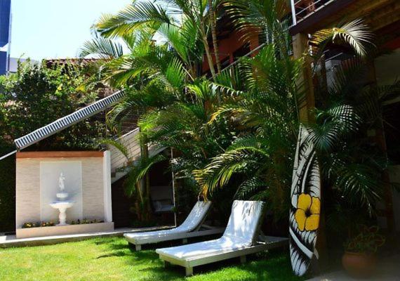 a group of benches next to a building with palm trees at Break House Beach in Florianópolis