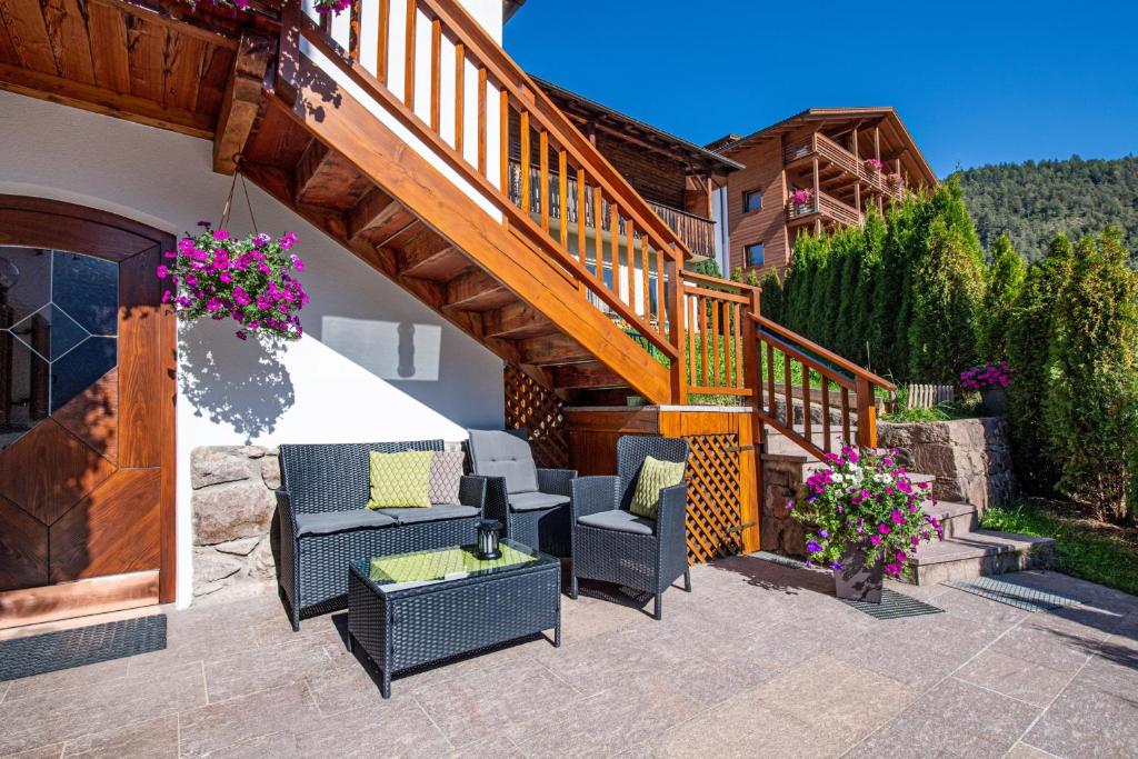 um pátio com cadeiras e uma escadaria com flores em Apartment Sellablick em Ortisei