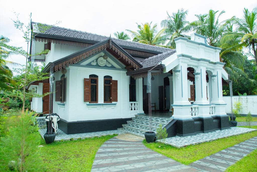een klein wit huis met bomen op de achtergrond bij Sea Turtles Bungalow in Bentota