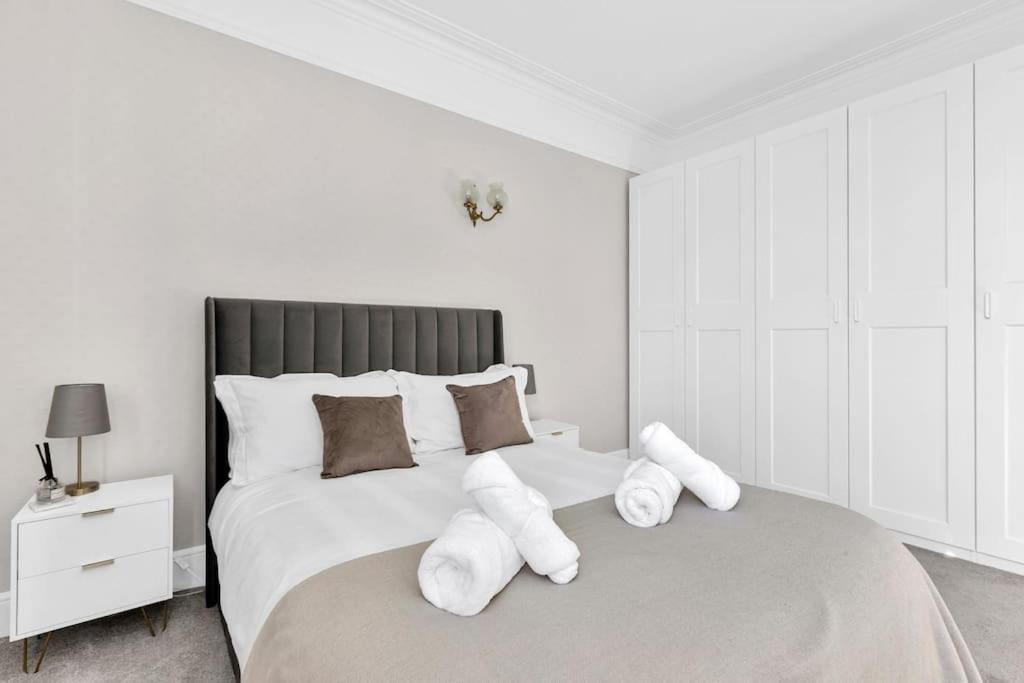 a white bedroom with a large bed with white pillows at Luxury 3 bedroom apartment in the heart of High Street Kensington, London. in London