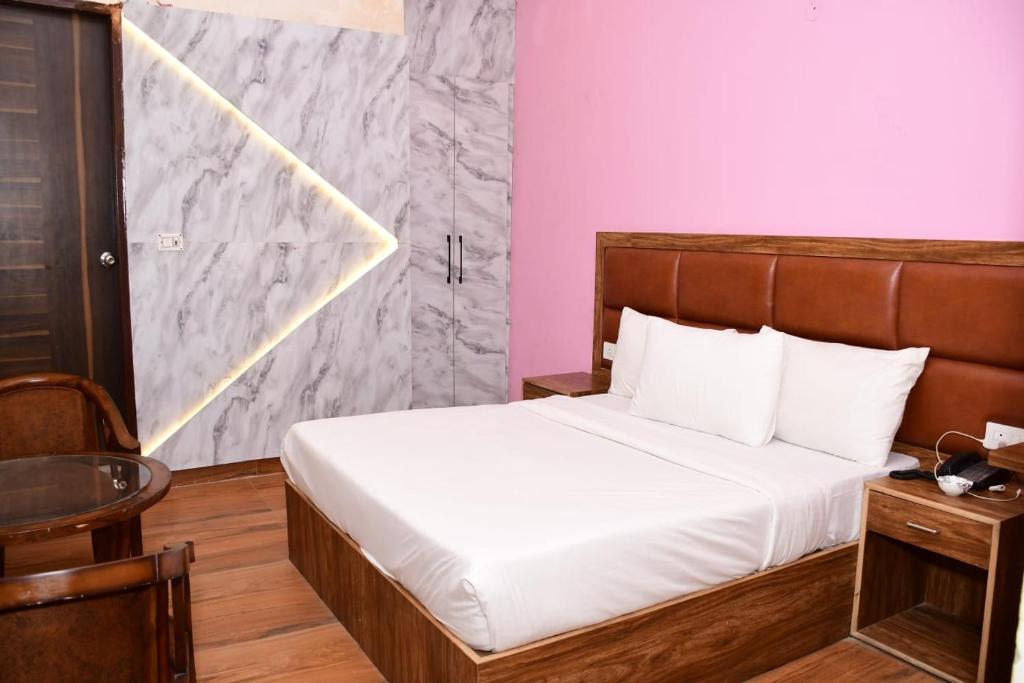 グレーター・ノイダにあるStiltstay Hotel, Greater Noidaのベッドルーム1室(白いシーツとピンクの壁のベッド1台付)