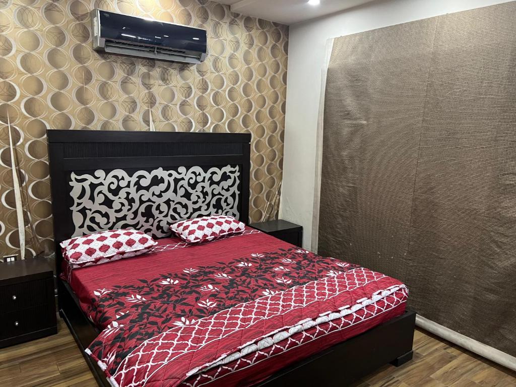 een slaapkamer met een rood bed met rode en witte kussens bij Prime Plaza in Gujrānwāla