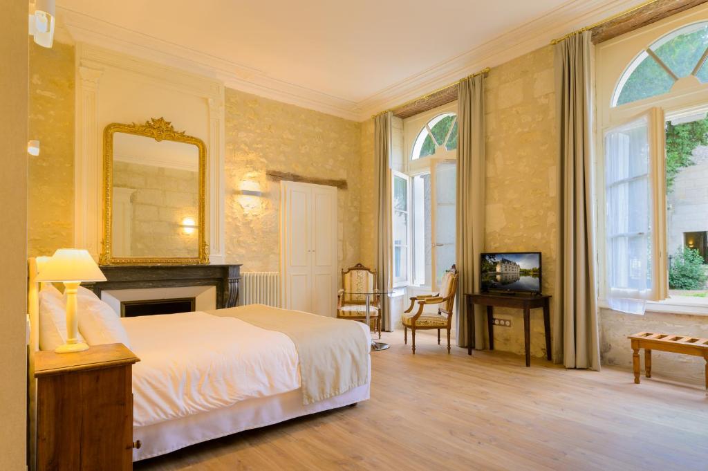 a bedroom with a bed and a mirror on the wall at Hôtel Grand Monarque in Azay-le-Rideau