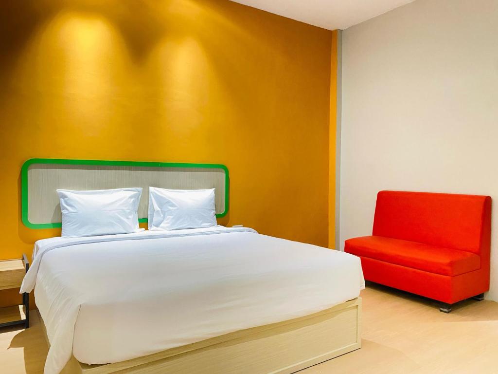 a bedroom with a bed and a red chair at Ruma Ruma Hotel Kenten - Palembang in Sukarami