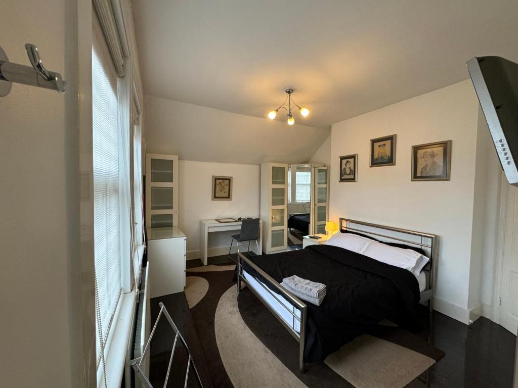 een slaapkamer met een bed en een bureau bij Luxury Cottage Room in Londen