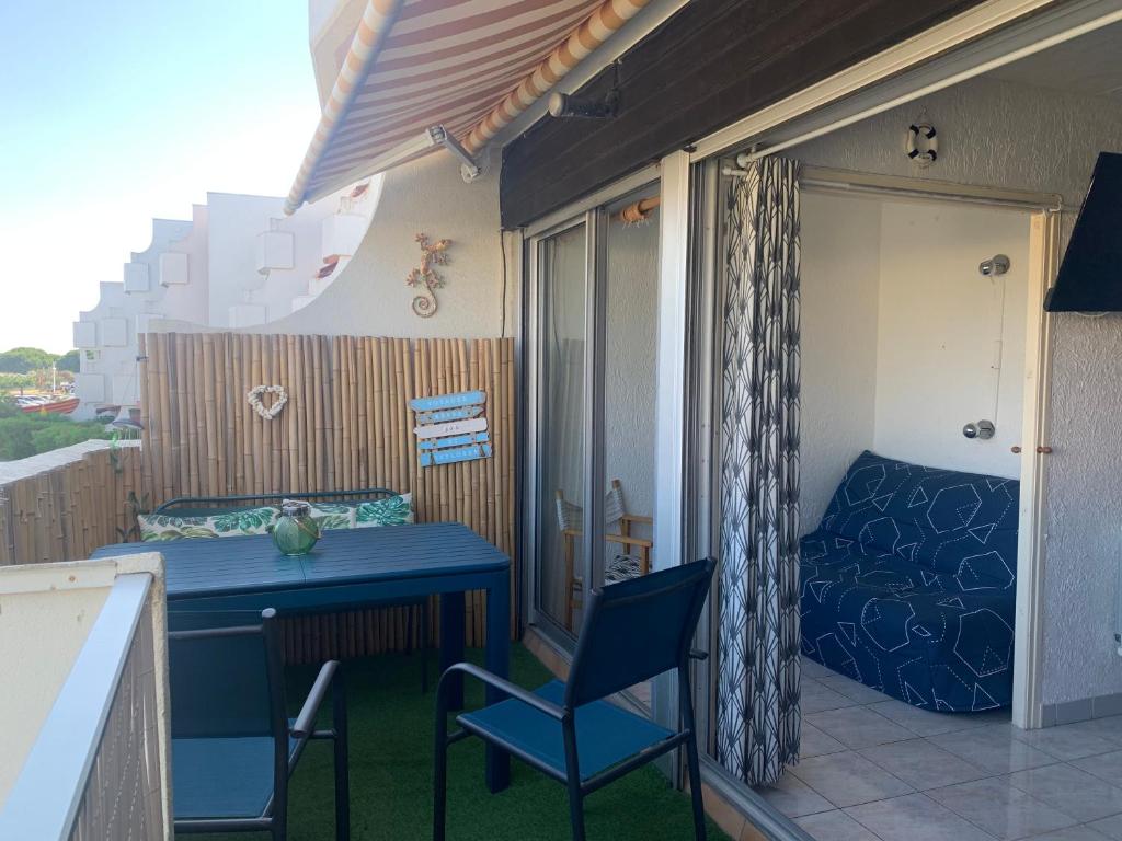 Elle comprend un balcon doté d'une table bleue, de chaises et d'un lit. dans l'établissement studio bord de mer, au Grau-du-Roi