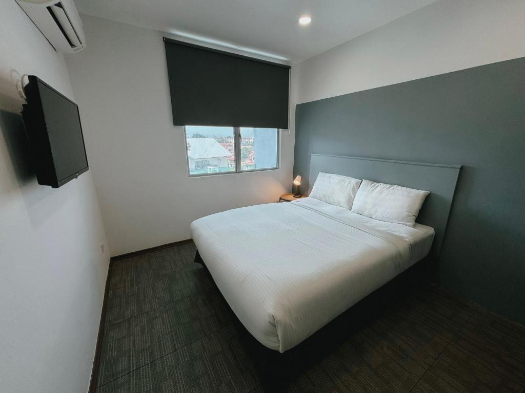 a bedroom with a white bed and a window at The Concept Hotel Melaka City in Melaka