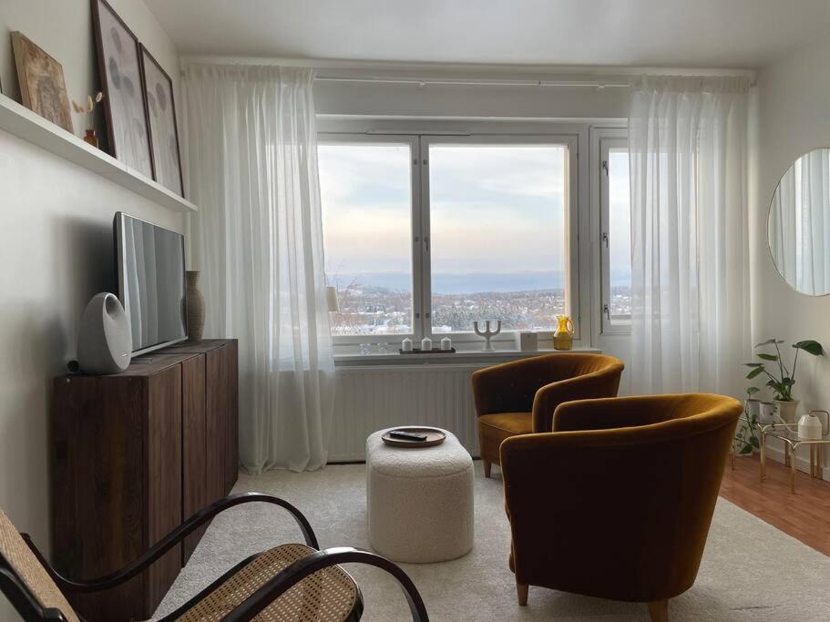 uma sala de estar com duas cadeiras e uma grande janela em Top floor apt with stunning view 