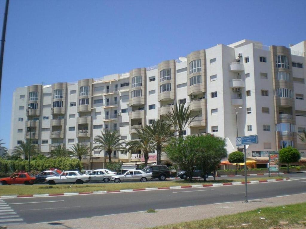 un grand bâtiment blanc avec des voitures garées devant lui dans l'établissement Résidence Borj-Dlalate City center Agadir, à Agadir