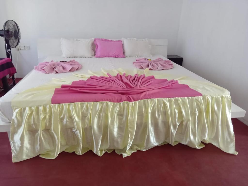 a large bed with pink and yellow sheets and pink pillows at New Gama Guest in Polonnaruwa
