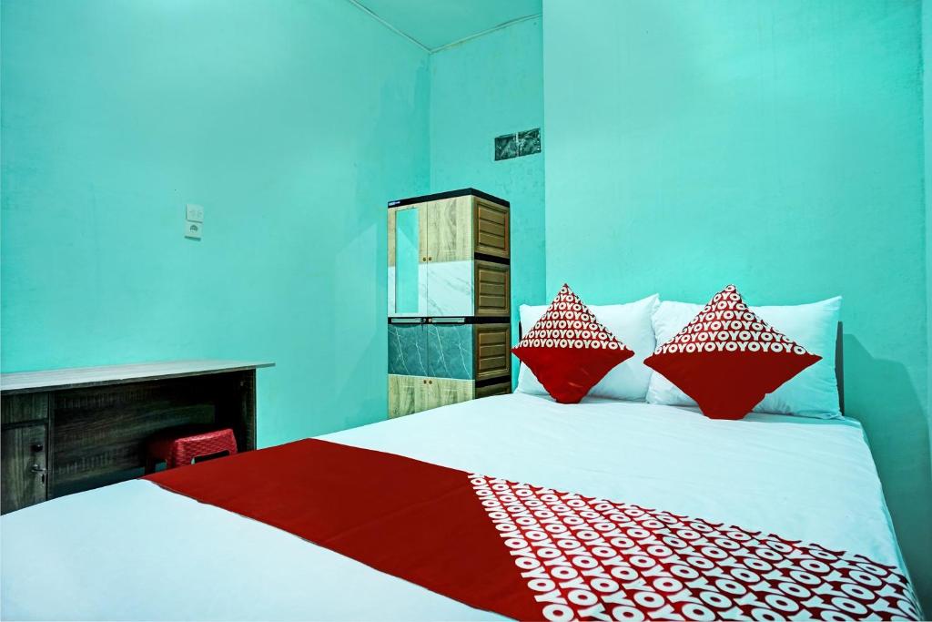 a bedroom with a bed with red and white pillows at OYO 93298 Barito House in Pematangsiantar