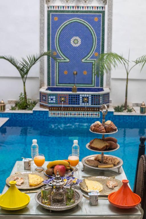 a table with food on it in front of a pool at Palais Chahd Luxury in Fez