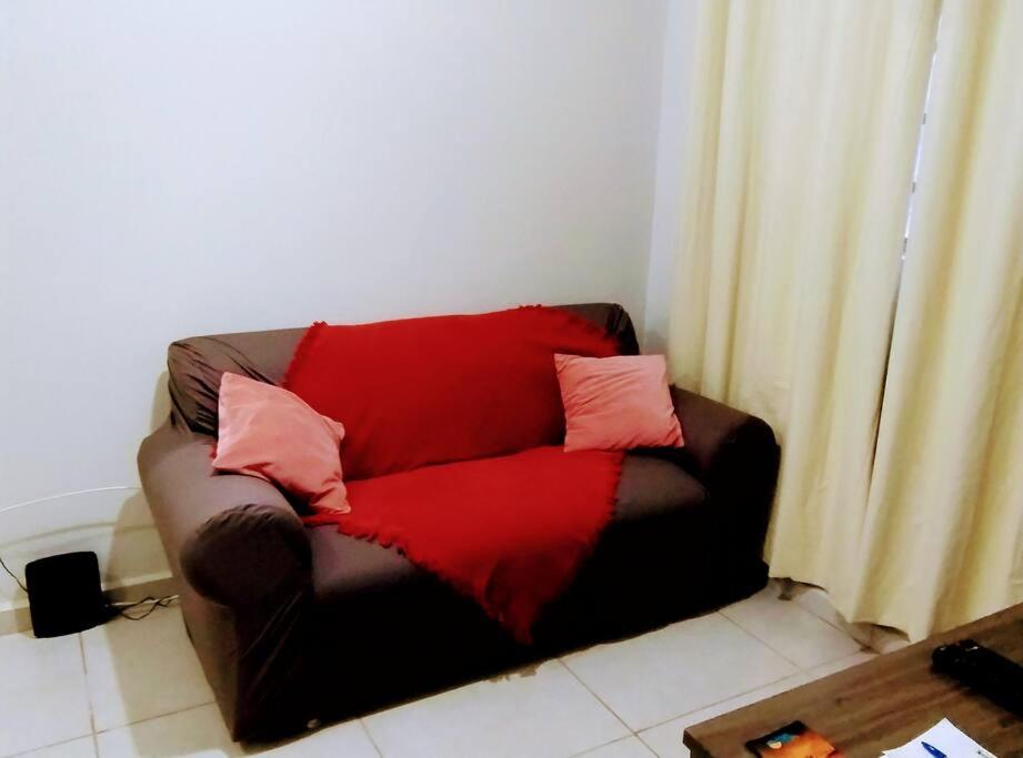 um sofá vermelho com almofadas num quarto em Apê Expô/ABQM - Cantinho Moraes em Araçatuba