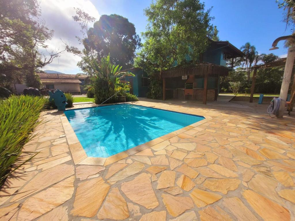 a swimming pool in a yard with a stone patio at Suítes Barra da Lagoa in Ubatuba