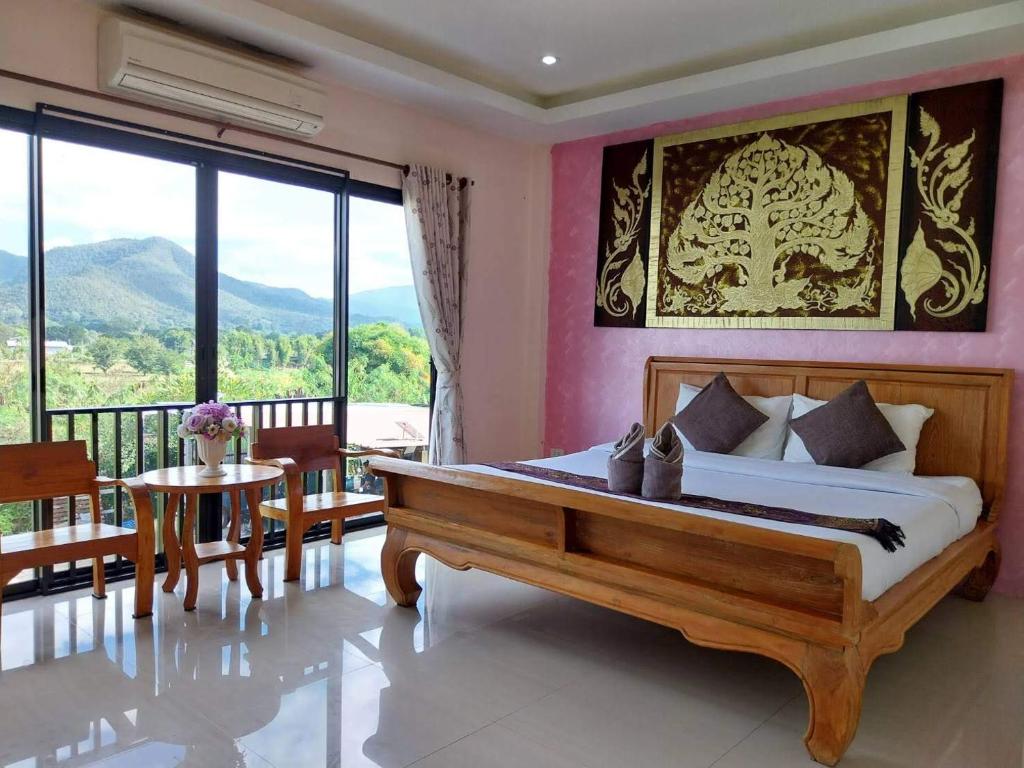 a bedroom with a bed and a table and a balcony at พลอยไพลินPLOYPAILIN in Pai