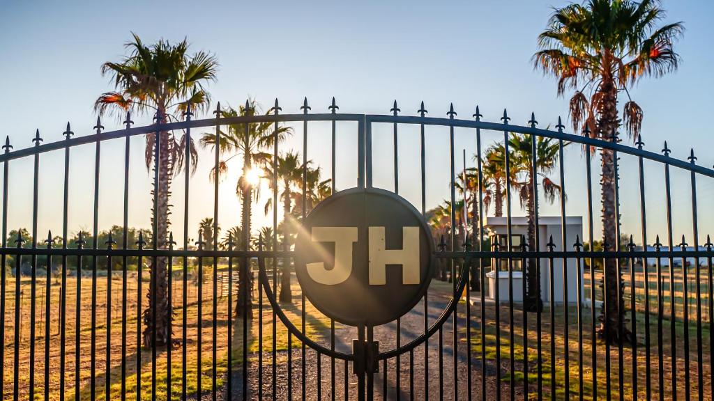 a gate with a sign on it with palm trees at Jonkershoek Guest Farm in Kimberley