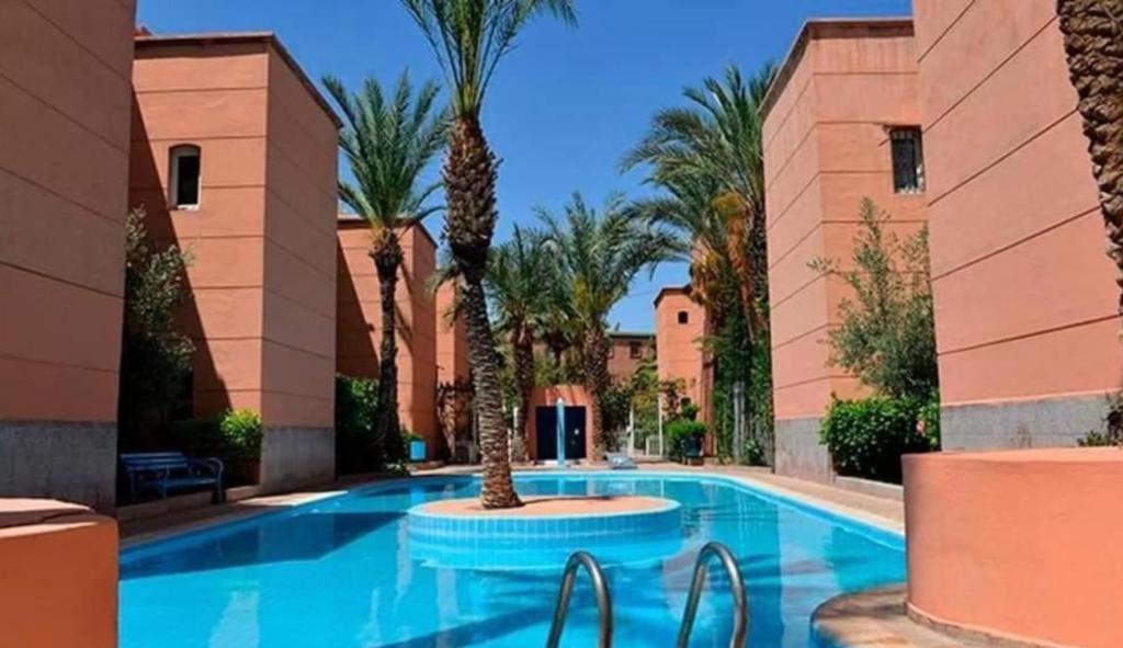 una piscina con palmeras en un complejo en Riad Nezha en Marrakech