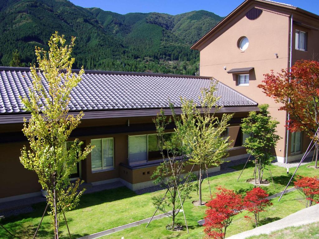 a house with mountains in the background at Gero Onsen Yukyunohana in Gero